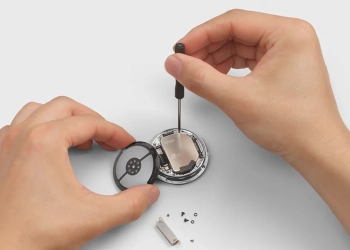Hands disassembling a Google Pixel Watch 4 with a screwdriver to replace its battery, showing the watch's serviceable design