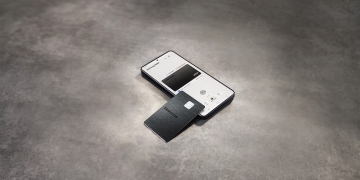 Samsung Galaxy Card in black metal resting on a Galaxy phone showing the card in Samsung Wallet