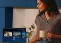 Woman using Alexa+ on an Echo Show smart display in an Indian kitchen, showing recommended recipes and smart home controls