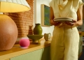Google Home speaker in pink on a kitchen sideboard, used with Gemini for Home voice commands
