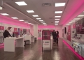 Interior of a T-Mobile retail store with pink lighting and phone display tables