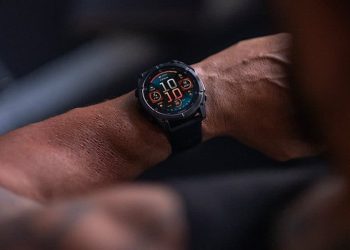 Garmin Fenix 8 AMOLED worn on a wrist showing its round watch face with orange and teal data fields