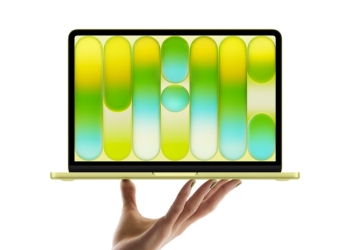 MacBook Neo in Citrus, open and balanced on a hand against a white background