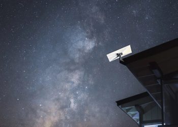 Starlink satellite internet dish mounted on a house roof under a starry night sky