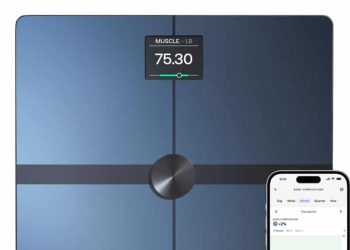 Withings smart scale with a dark glass top beside a phone showing body-composition data in the Withings app